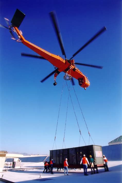 aerial crane helicopter positioning HVAC unit atop a skyscraper roof