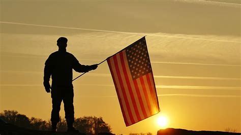 air force personnel saluting flag at sunset on flight line
