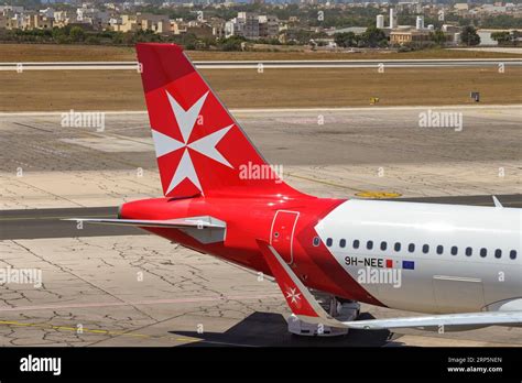 Air Malta tail fin with Maltese cross logo against blue sky at sunset