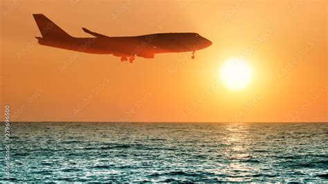 Airbus A350 ultra long haul aircraft flying above ocean sunset