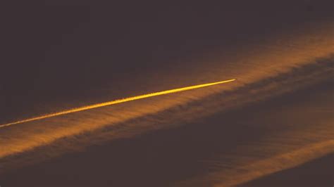 airbus a380 climbing over city skyline during sunset with contrails