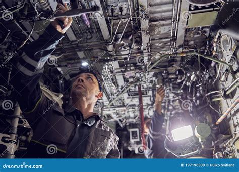aircraft maintenance crew inspecting jet engines inside hangar