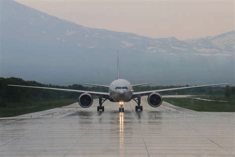 Aircraft taxiing slowly on wet tarmac at Perth Airport during bad weather-related delays