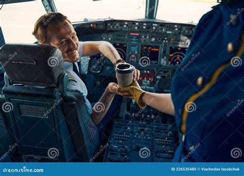 airline pilot holding coffee inside cockpit during overnight cruise flight