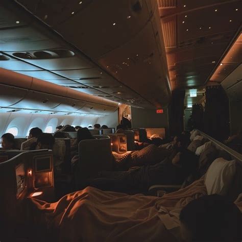airplane cabin night passengers sleeping blankets overhead bins closed