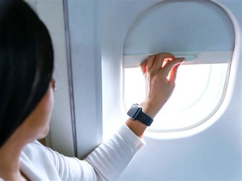 airplane passenger adjusting window shade sunlight cabin balance