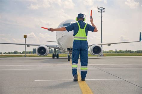 airport employees in safety vests walking on tarmac near Delta Airlines plane in Savannah