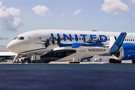 archer aviation and united airlines executives shaking hands at united hub with midnight aircraft in background