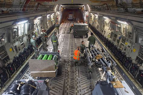 armored vehicle loaded inside c17 cargo hold secured with tie down straps