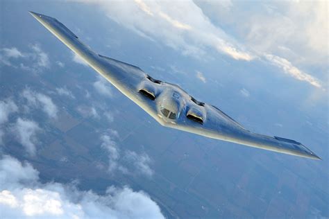 B-2 Spirit flying wing bomber banking over clouds at high altitude