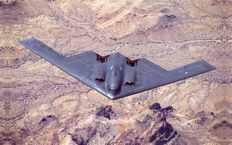 B-2 Spirit flying-wing bomber over sunset-lit desert