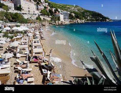 Banje Beach with view of Dubrovnik walls and umbrellas along pebbled shoreline