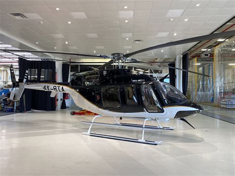 Bell 407 GXi flying over mountainous terrain in 2024 with corporate livery