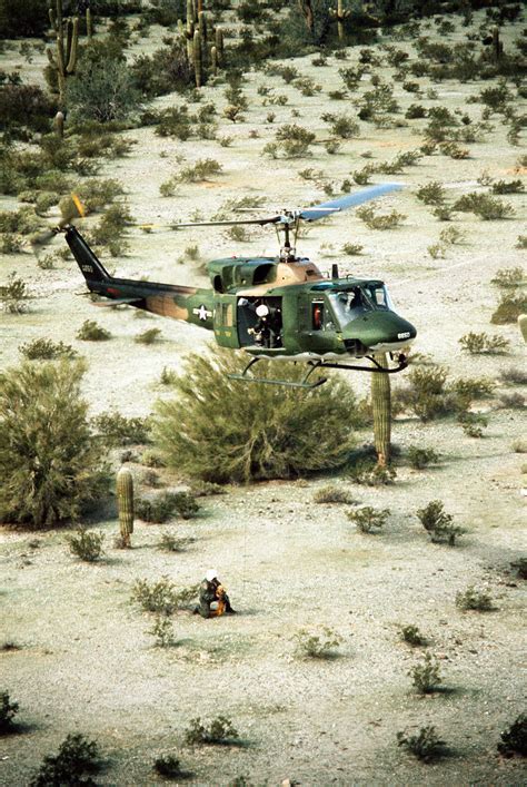 bell uh-1 iroquois helicopter landing in desert environment with soldiers disembarking