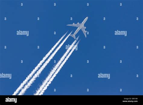 boeing 747-8i cruising at high altitude with visible contrails over ocean