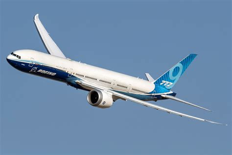 boeing 777x takeoff with extended wingspan under clear sky