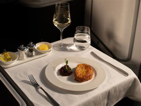 british airways first class meal with wine pairing and white table linens