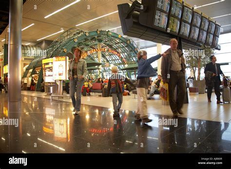 busy interior of Schiphol Airport terminal with departure screens and passenger activity