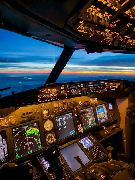 calm airline cockpit at cruise altitude pilots monitoring instruments sunset sky