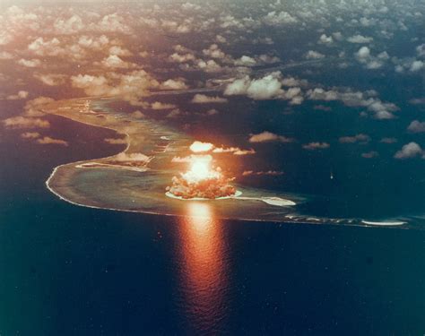 Castle Bravo mushroom cloud towering over Bikini Atoll with vaporized islands in foreground