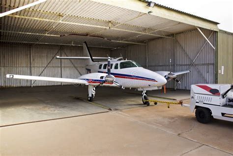 Cessna 140 parked beside a hangar with sun setting behind its metal wing frame