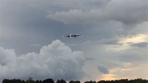 cessna 310 on short final approach at rural airstrip with tip tanks visible