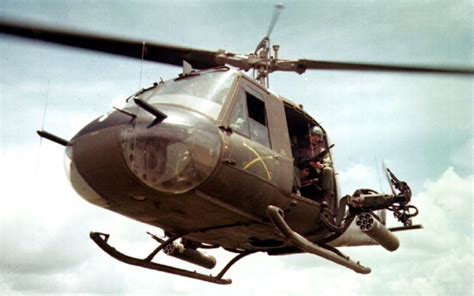close-up of Huey helicopter side door gunner with spinning rotors above during landing sequence