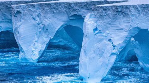 close-up of polar boots and red parka against ice-blue backdrop of Antarctic glacier