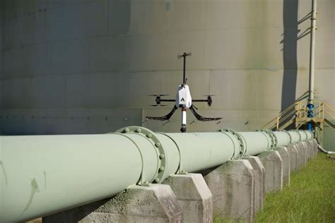 commercial drone pilot operating aerial inspection drone over industrial facility