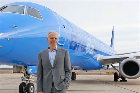 david neeleman speaking at breeze airways event with a220 in background