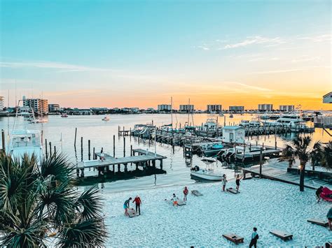 Destin harbor boardwalk with waterfront cafes and fishing boats in early evening light
