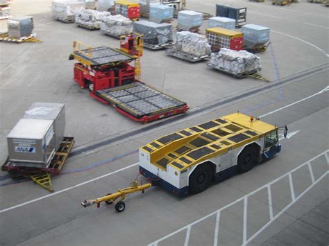 diverse ground support fleet with pushback tugs and towbars lined up under hangar