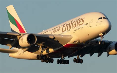 emirates airbus a380 in flight over dubai skyline at sunset