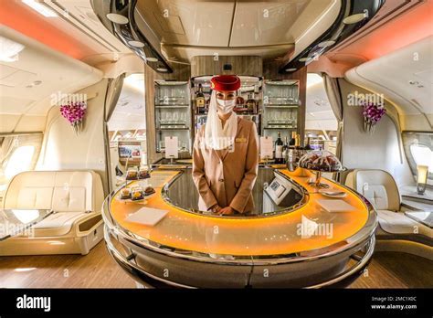 emirates onboard service crew in first class section with purser welcoming passenger