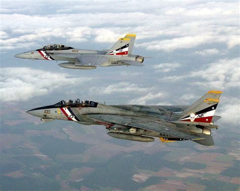 F-14 Tomcat parked next to an F/A-18 Super Hornet on a naval airfield