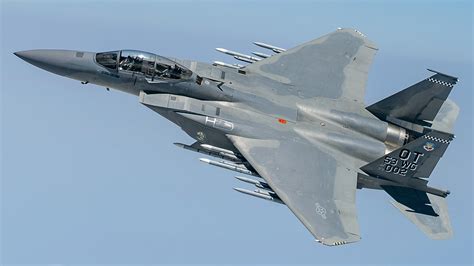 f-15 eagle armed with amraam and sidewinder missiles banking over pacific ocean