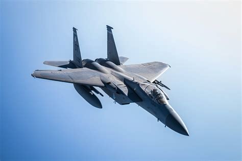 F-15 fighter jet banking mid-air with wings under load stress during combat training