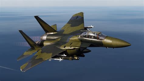 F-15E with green and gray camouflage flying over European woodlands