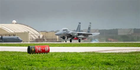 F-15EX taxiing on runway at Kadena Air Base with F-35s in background