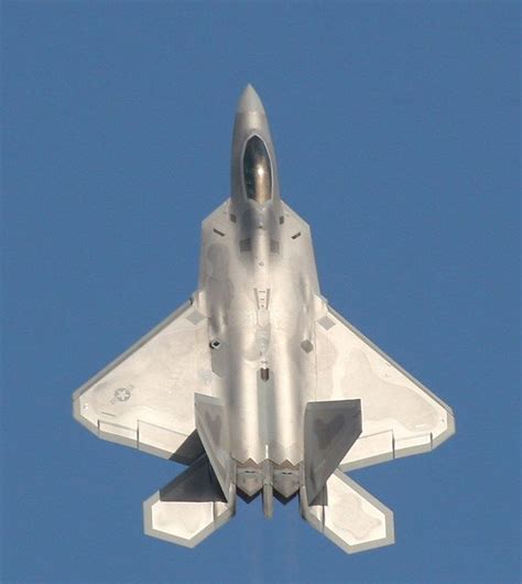f-22 raptor climbing vertically with contrails in clear blue sky