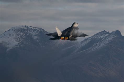 F-22 Raptor performing high angle of attack maneuver with thrust vectoring nozzles visible