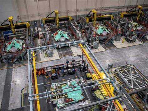 F-35 assembly line technicians working on fuselage with missing components