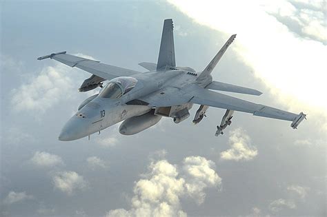 F/A-18F Super Hornet flying over a combat zone