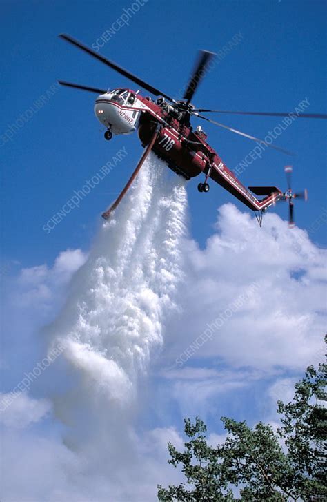 firefighting helicopter dropping water over forest blaze