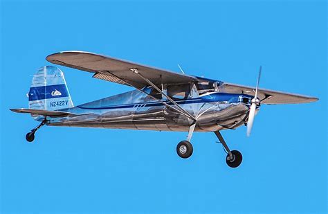 flying cessna 140 cruising over rural farmlands