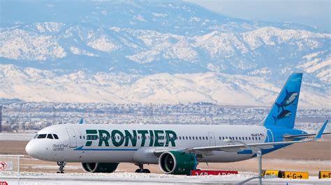 Frontier Airlines jet departing from a busy U.S. airport under cloudy skies