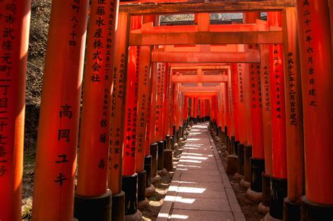 Fushimi Inari Shrine in Kyoto with red torii gates and tourists in summer