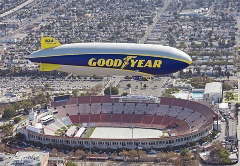Goodyear blimp hovering over stadium during daytime event