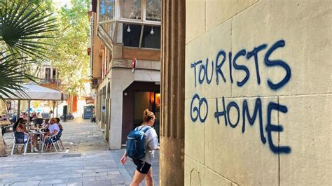 graffiti on wall in barcelona warning tourists to go home summer tourism crisis 2025
