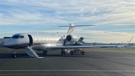 Gulfstream G650 private jet on runway with luxury limousine nearby